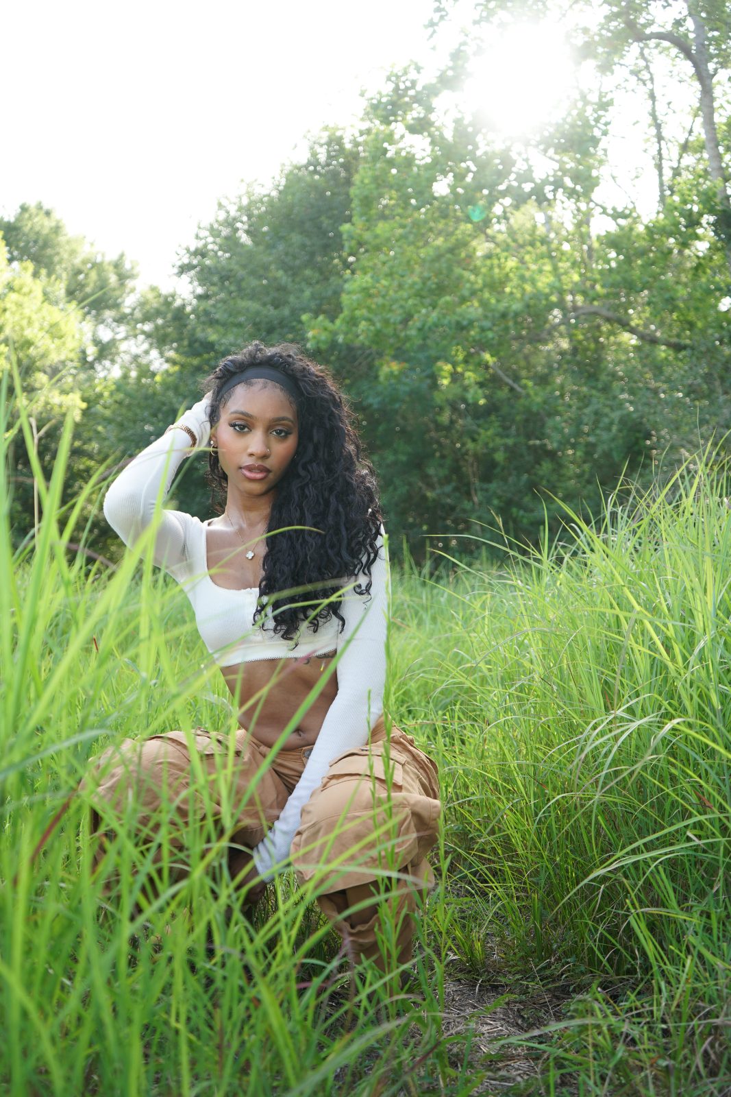 Outdoor fashion portrait in tall grass, white knit and tan cargo trousers