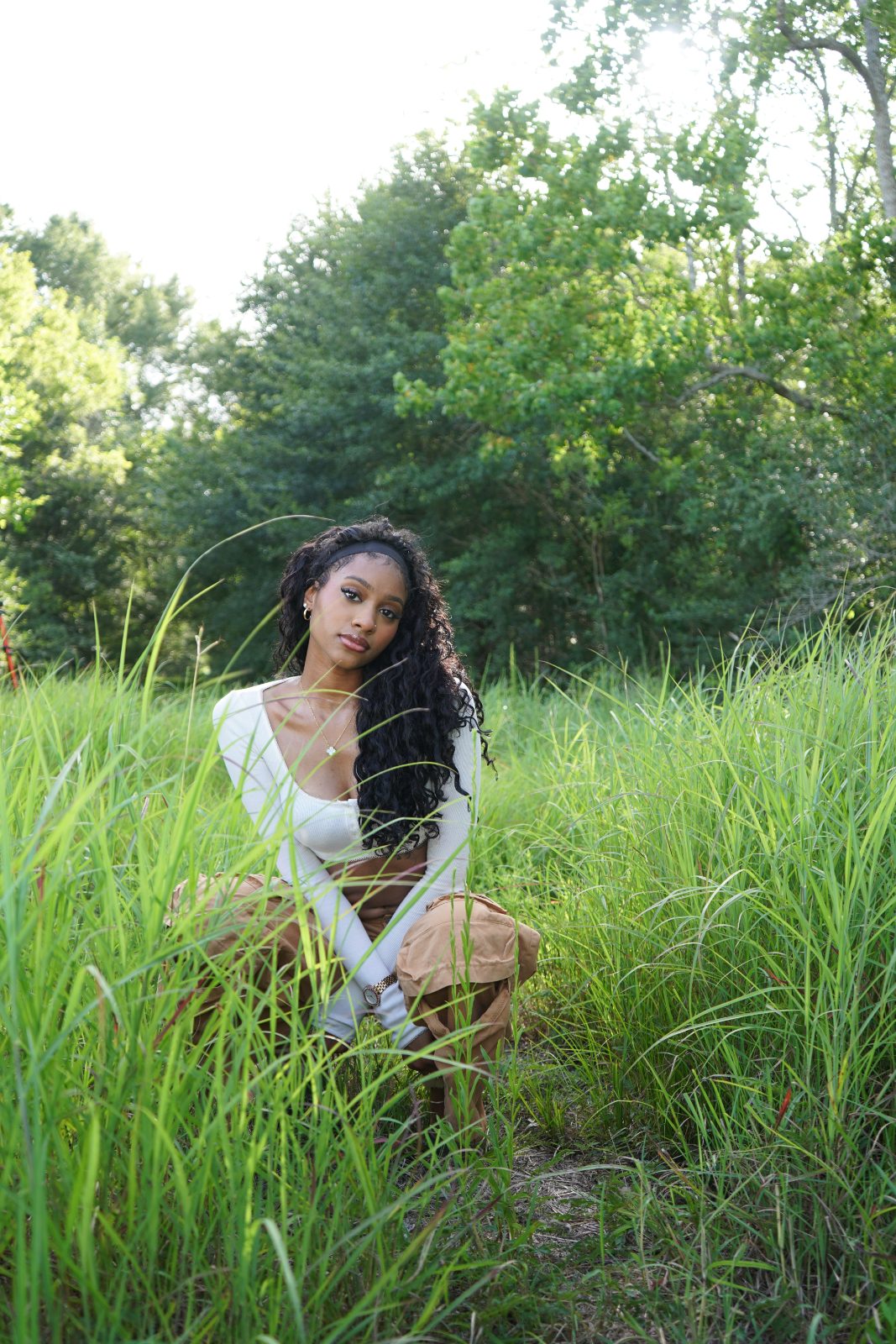 Outdoor fashion portrait in tall grass, white knit and tan cargo trousers