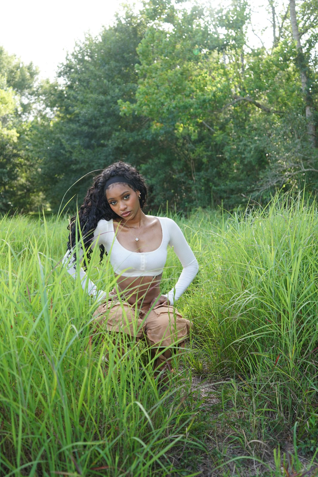 Outdoor fashion portrait in tall grass, white knit and tan cargo trousers
