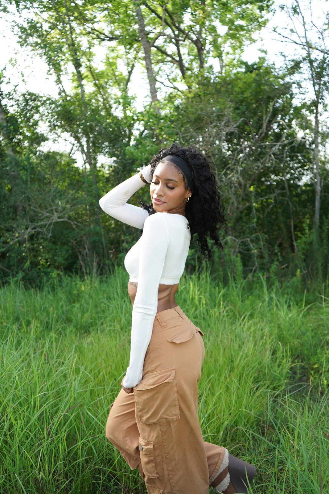 Outdoor fashion portrait in tall grass, white knit and tan cargo trousers