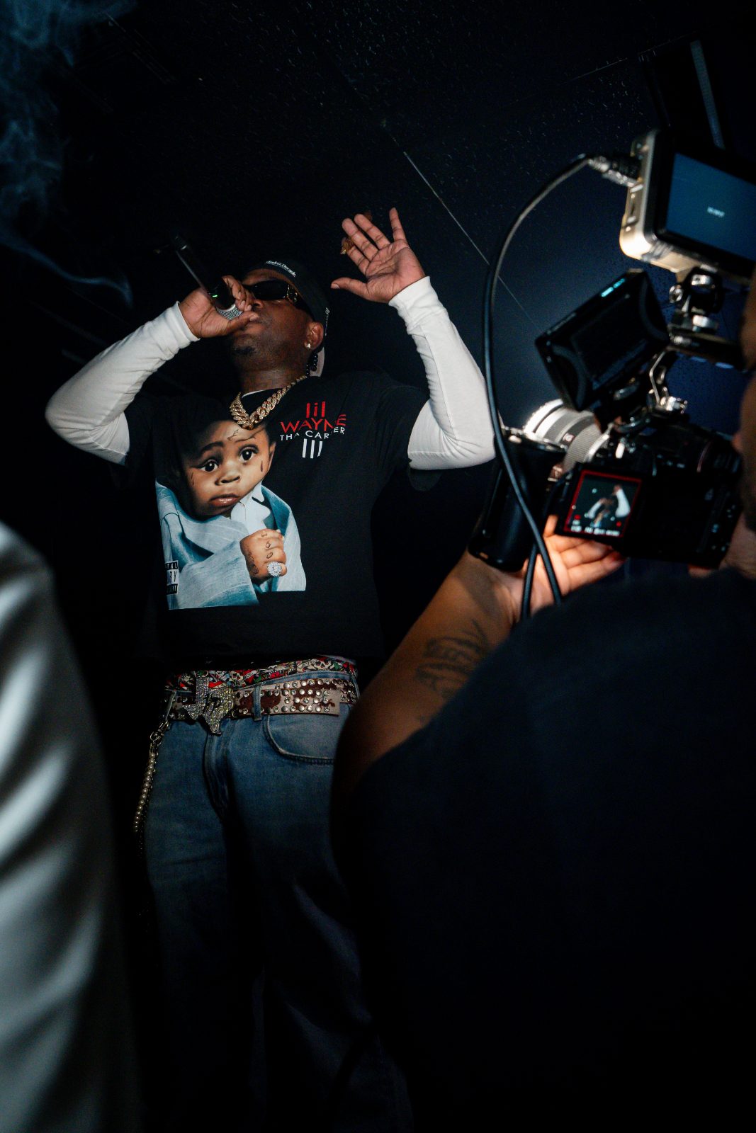 Rapper mid-verse under hard stage light, cigar smoke in the beam