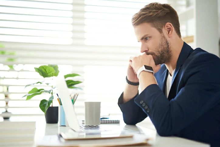 homme pensif regardant dans un ordinateur portable