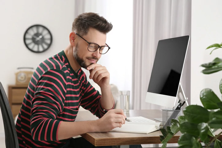 homme à lunettes écrivant dans un agenda
