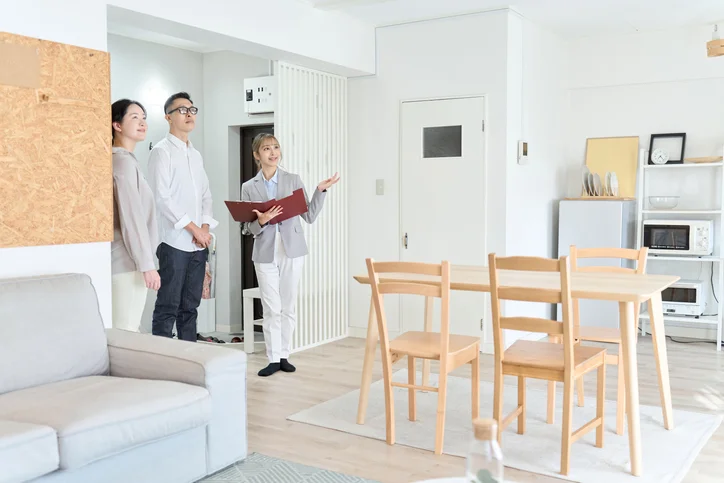 Un couple qui visite un appartement à côté d'une professionnelle de l'immobilier.