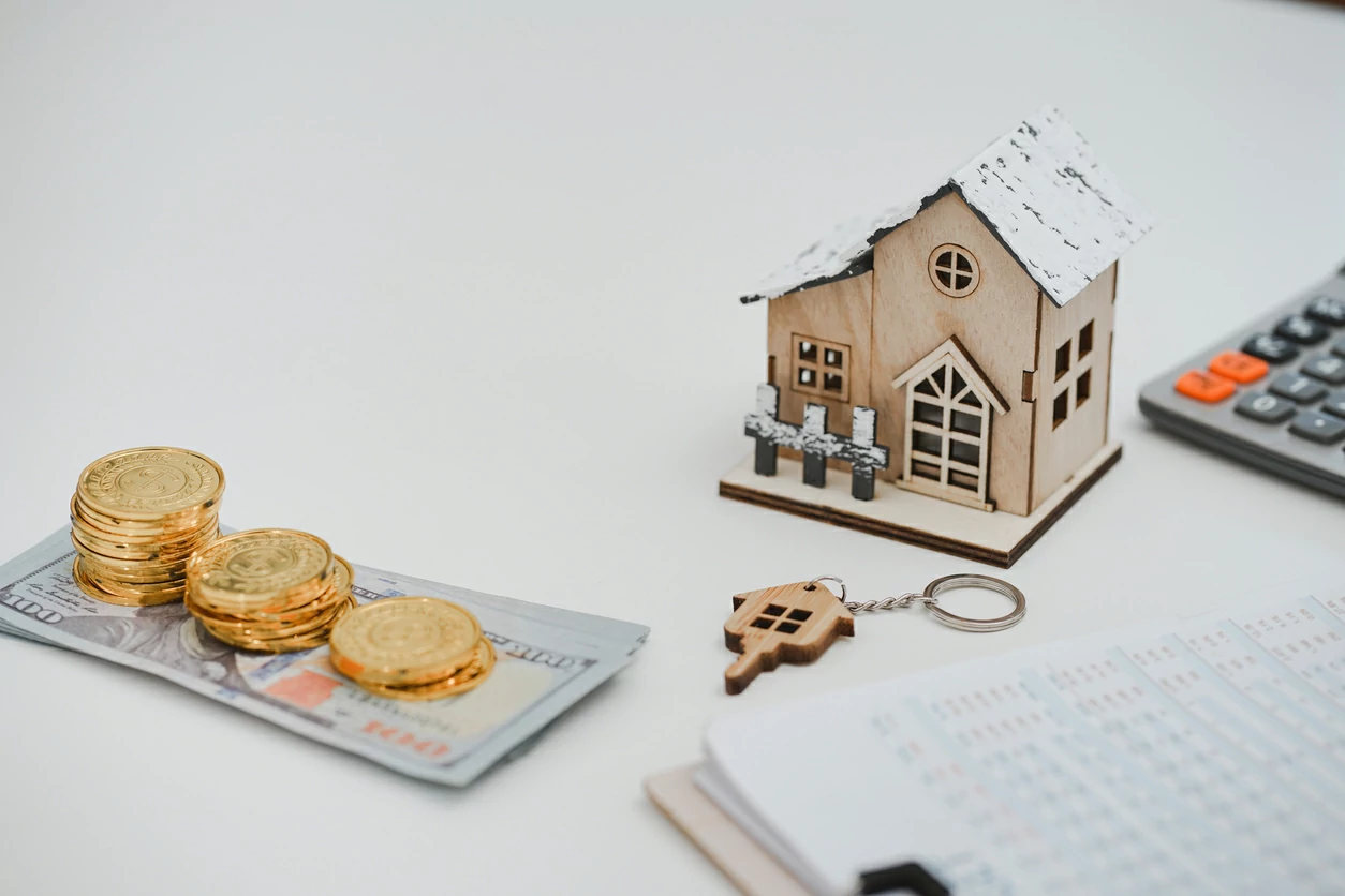 Petite maison, calculatrice, clé de maison, documents et de l'argent en billet et en pièce.