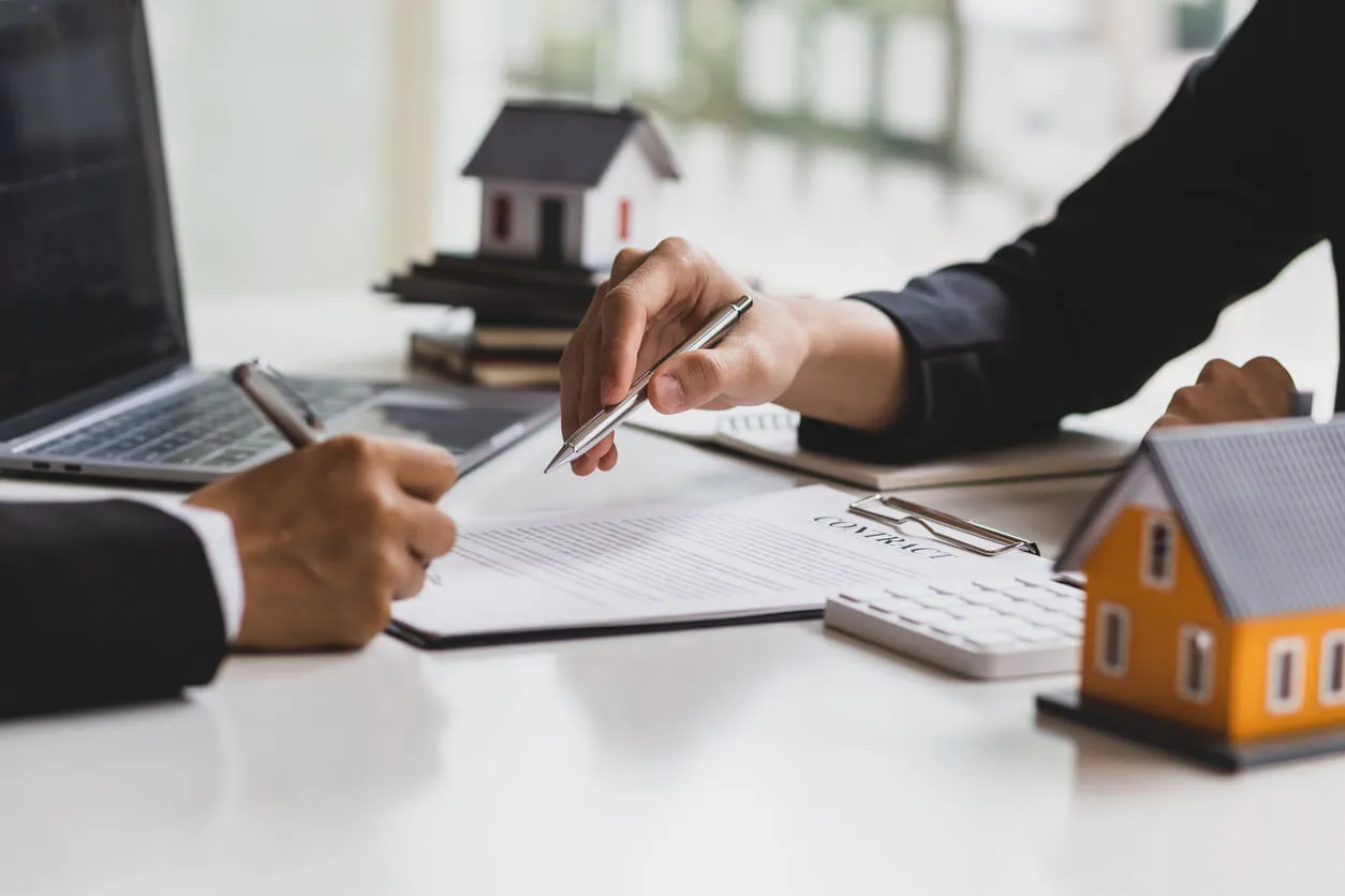 Main signant un document et autre main tenant un stylo qui indique l'emplacement.