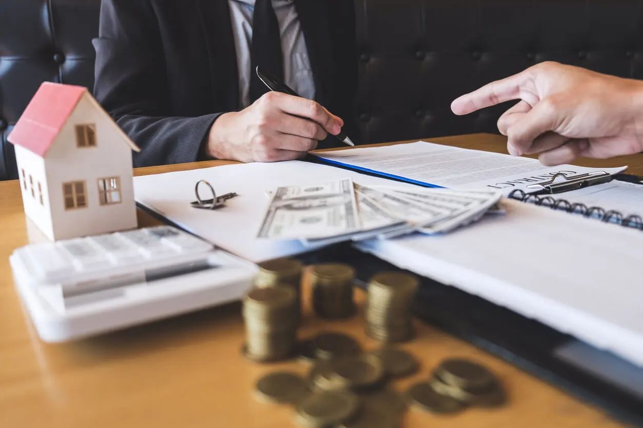 Main qui pointe sur un document et autre main tenant un stylo qui s'apprêt à signer le document.