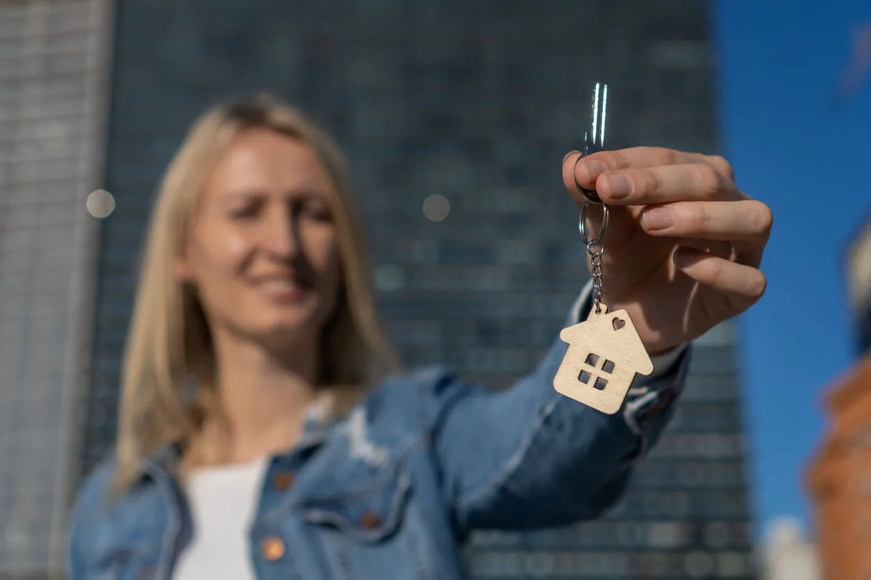 Femme souriante qui tient une clé de maison.