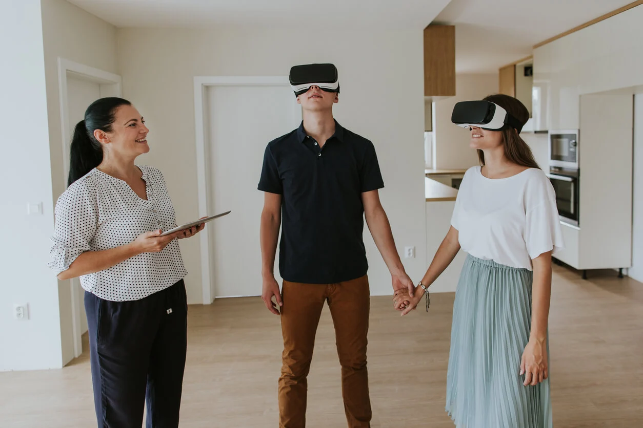 Agent immobilier et couple en visite virtuelle avec des casques VR.
