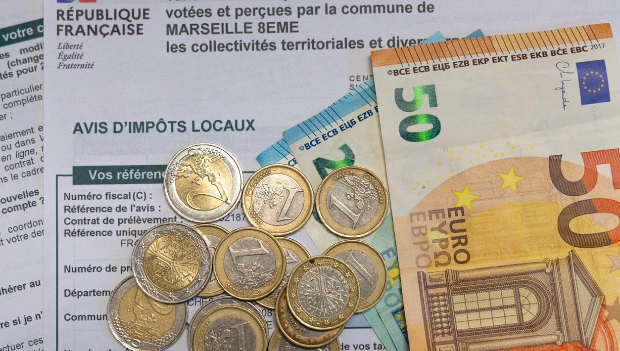 Pièces de monnaie et billet d'argent posés sur un formulaire d'impôt.