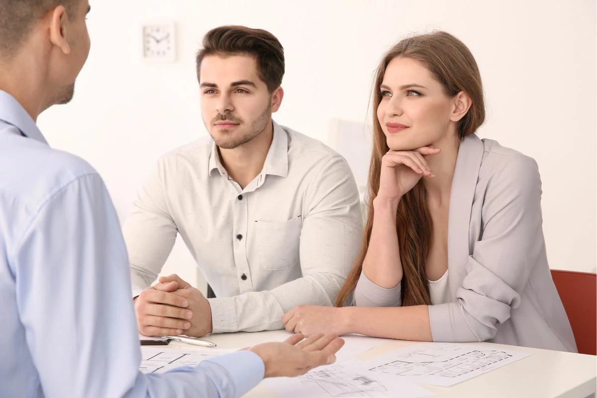 Homme et femme avec un air concentré devant un homme un peu plus âgé et des documents.