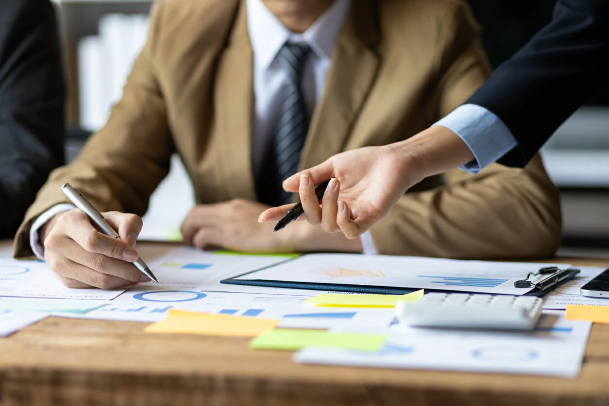 Homme consultant des documents et une main qui indique un emplacement précis.