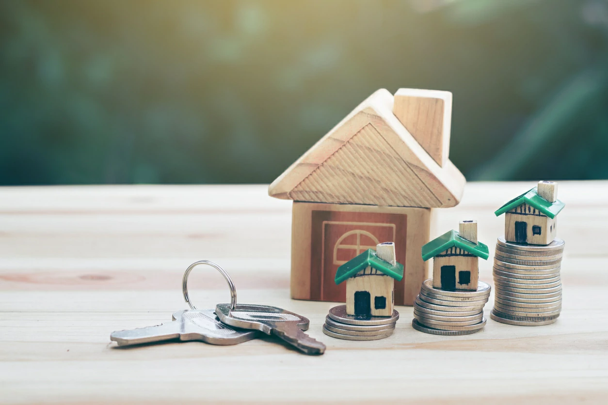 Piles de pièces de monnaie, clé, maison en bois