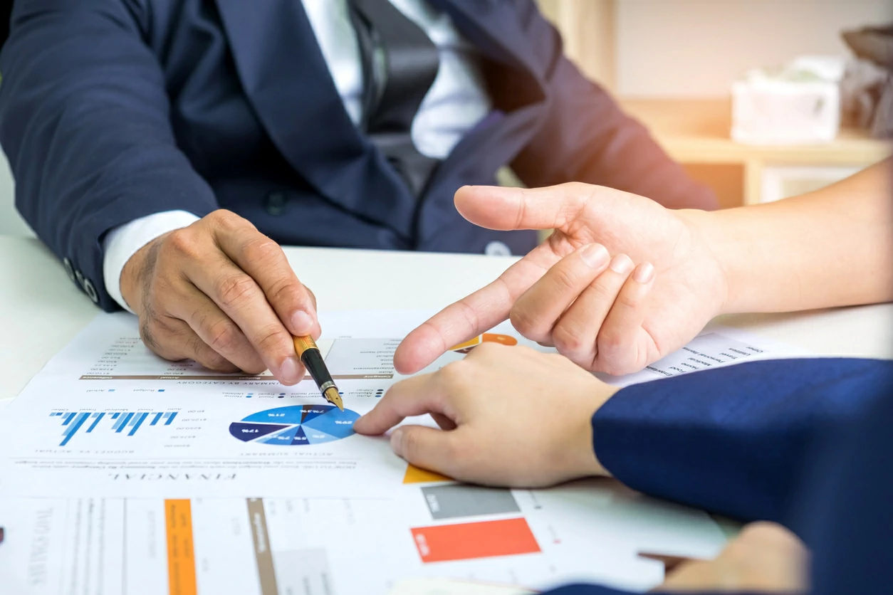 Deux personnes pointant une graphique circulaire avec un stylo et un doigt.