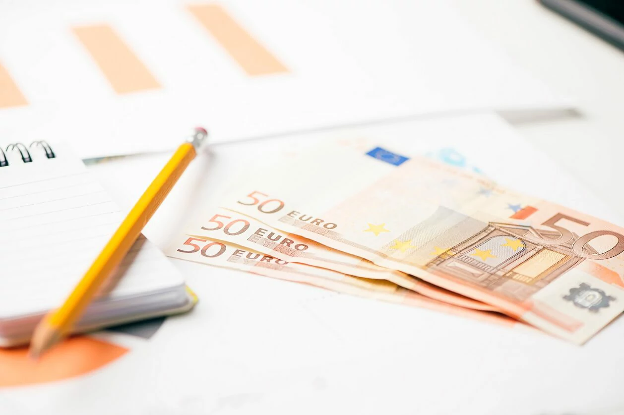 Plusieurs billets de 50 euros, un bloc-notes et un crayon.