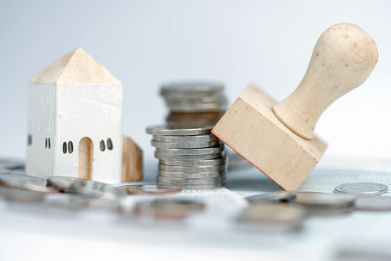 Petite maison en bois sculpté, des pièces de monnaie et un cachet.