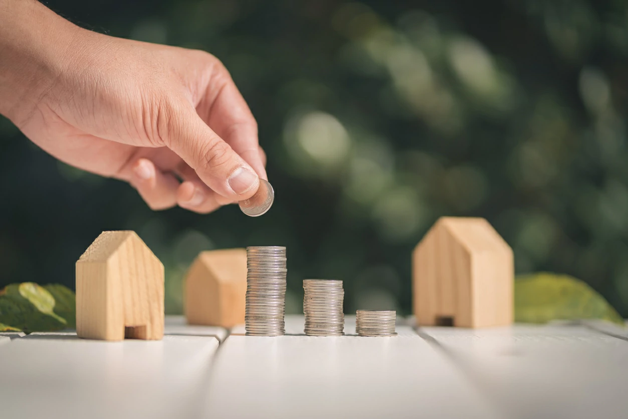 Main qui place une pièce de monnaie sur une pile de pièce de monnaie.