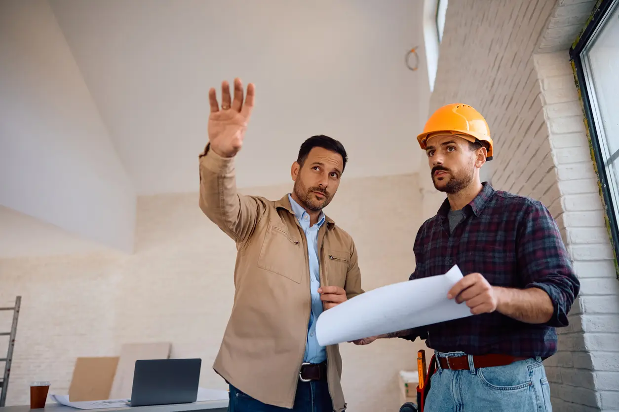 Professionnel du BTP tenant un document à coté d'un homme en pleine explication.