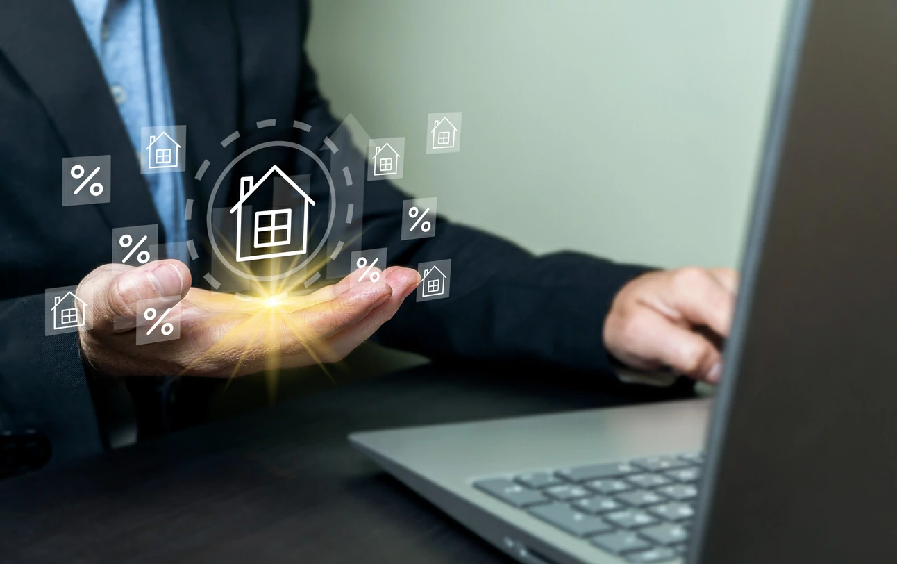 Homme manipulant un ordinateur portable de la main droite et des hologrammes de maison dans la main gauche.