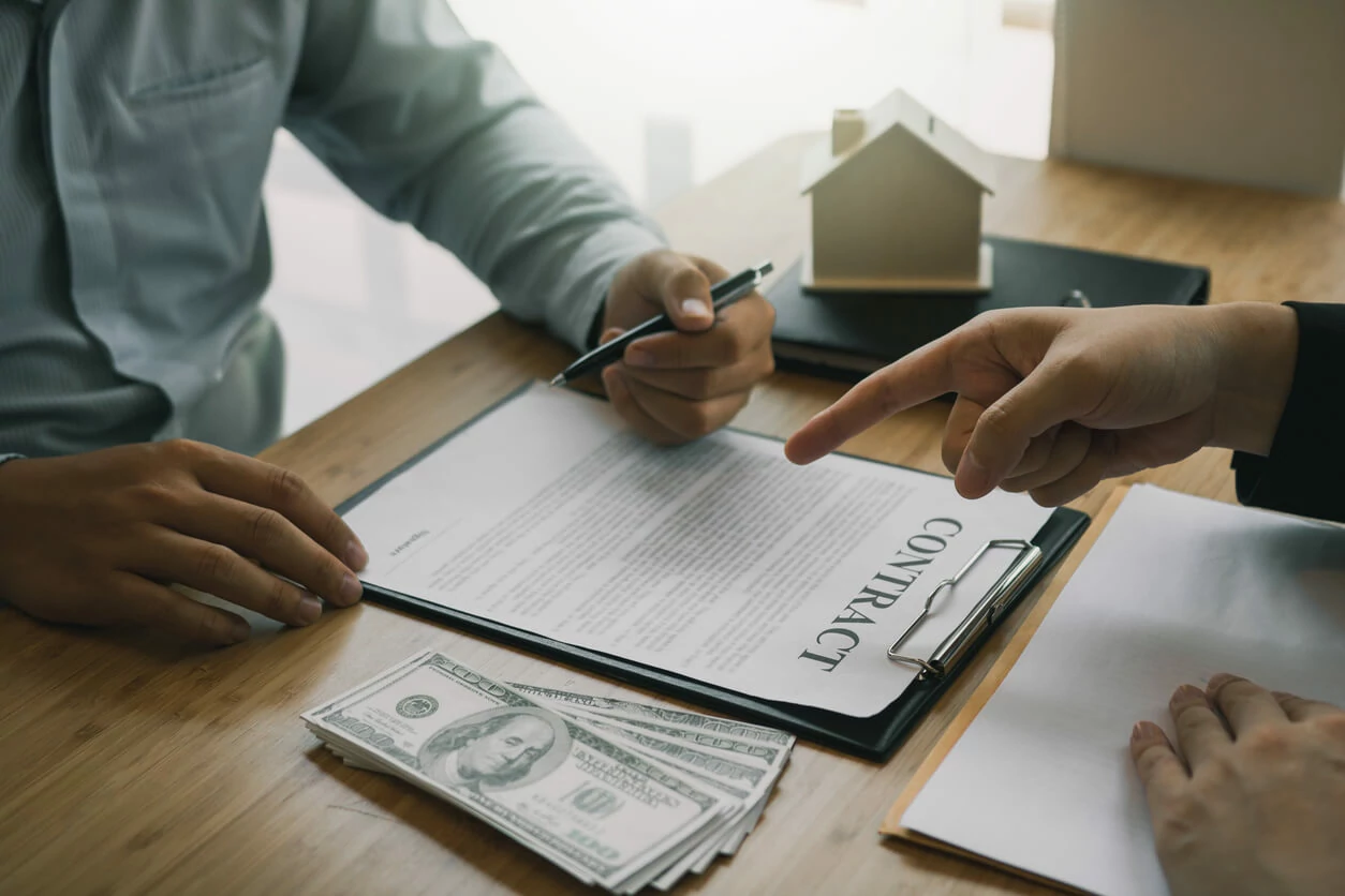 Homme pointant un document de la main devant un homme qui s'apprête à signer le document.