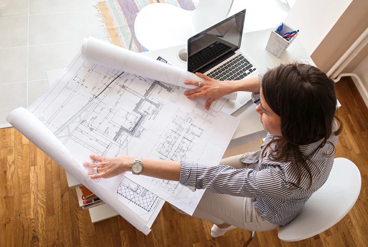 Femme consultant des plans sur un bureau.