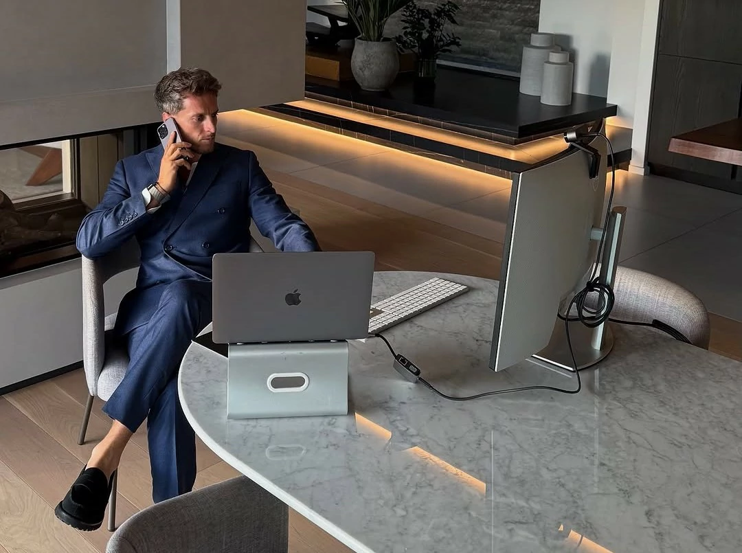 Christopher Wangen assis sur un bureau en train de téléphoner avec un smartphone.