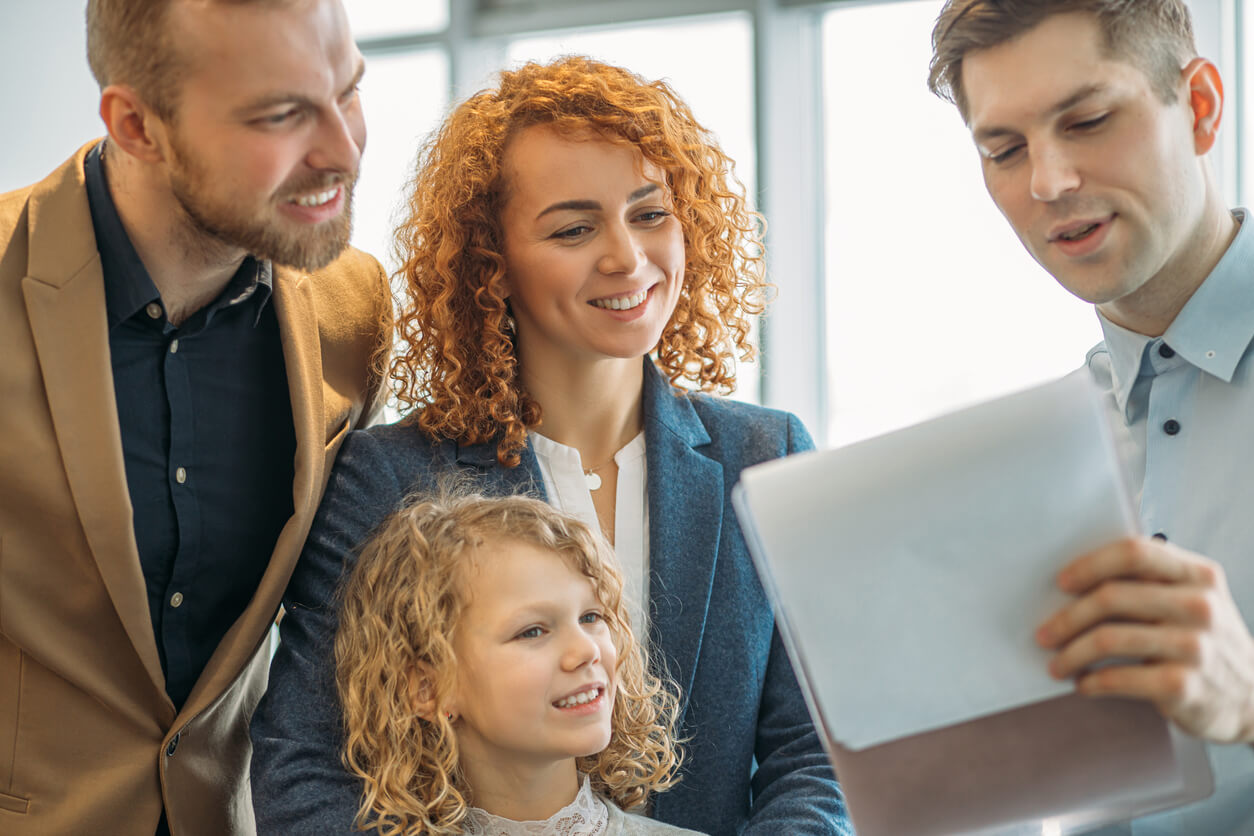 Professionnel immobilier montrant des documents Ă une famille de trois personnes.
