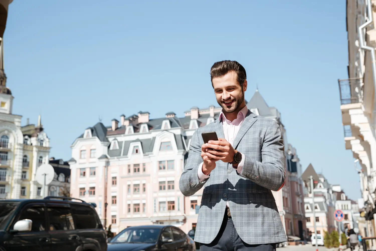 Homme d'affaires souriant qui regarde son smartphone.