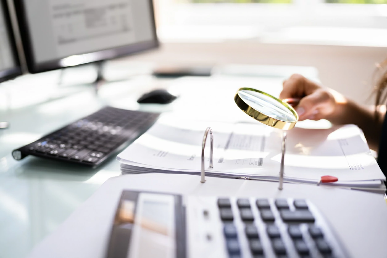 Main tenant une loupe au dessus d'un document.