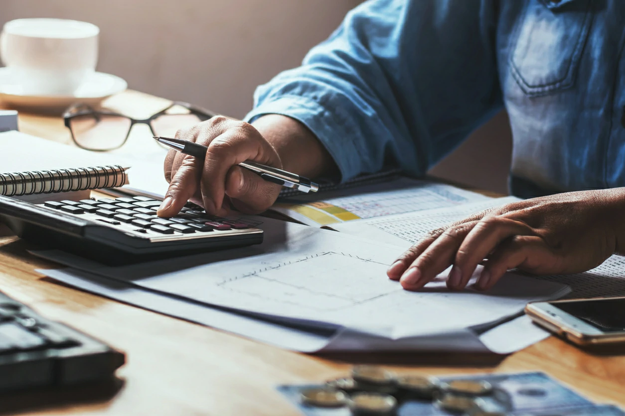 Homme faisant des calculs sur une calculatrice avec un stylo à la main
