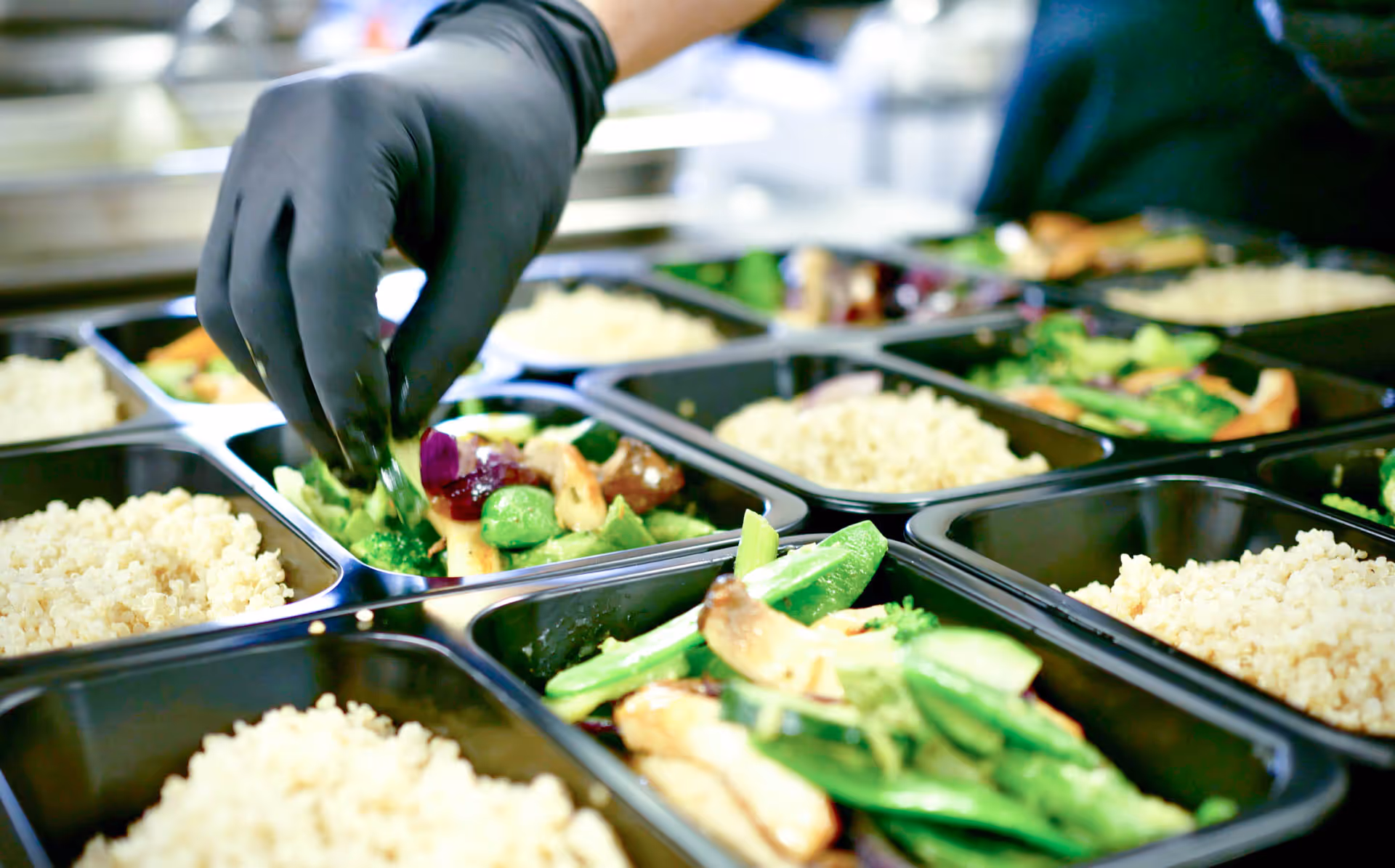 Unsere Schalen werden von einem Mitarbeiter mit frischem Gemüse und Reis befüllt. 