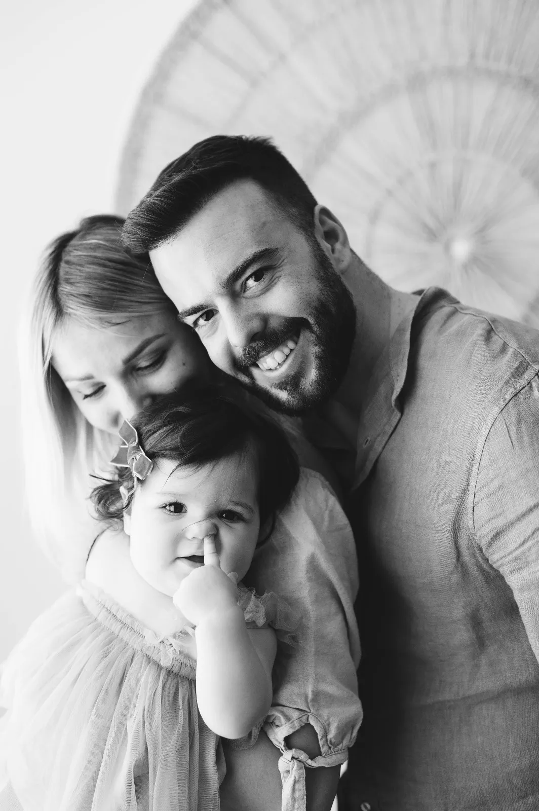 Servizio fotografico bebè in bianco e nero: mamma e papà sorridono con la bimba in braccio in studio