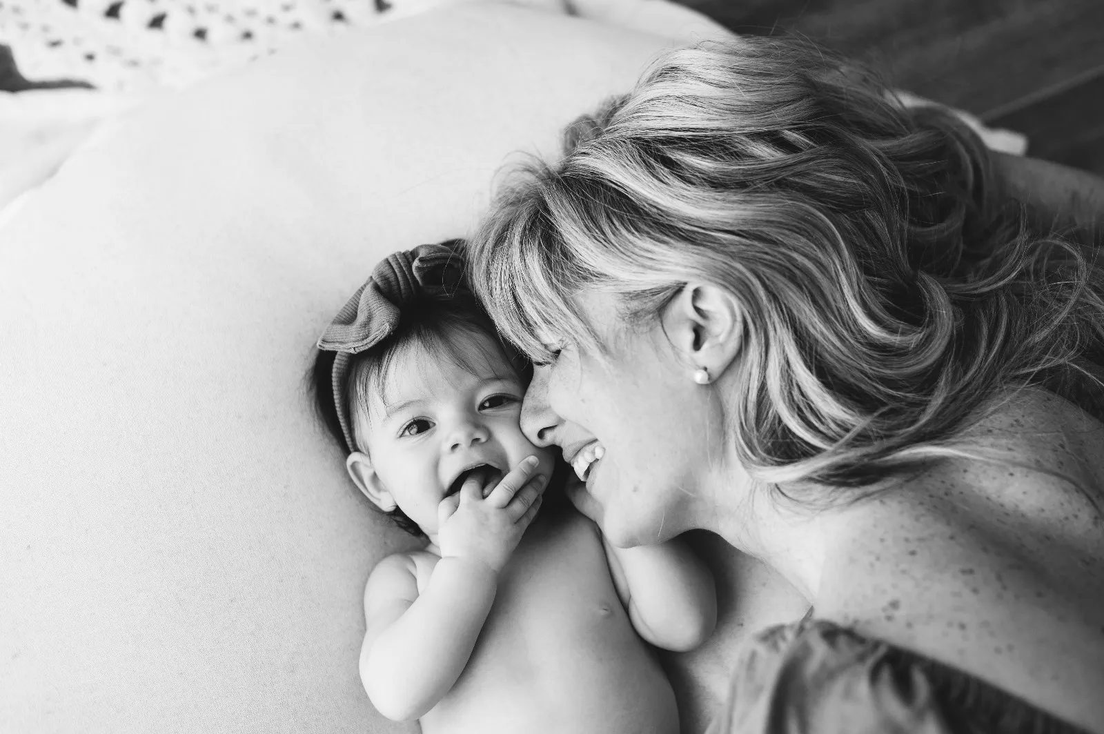 Sessione mamma e figlio in bianco e nero: mamma e bebè distesi sul letto che ridono insieme