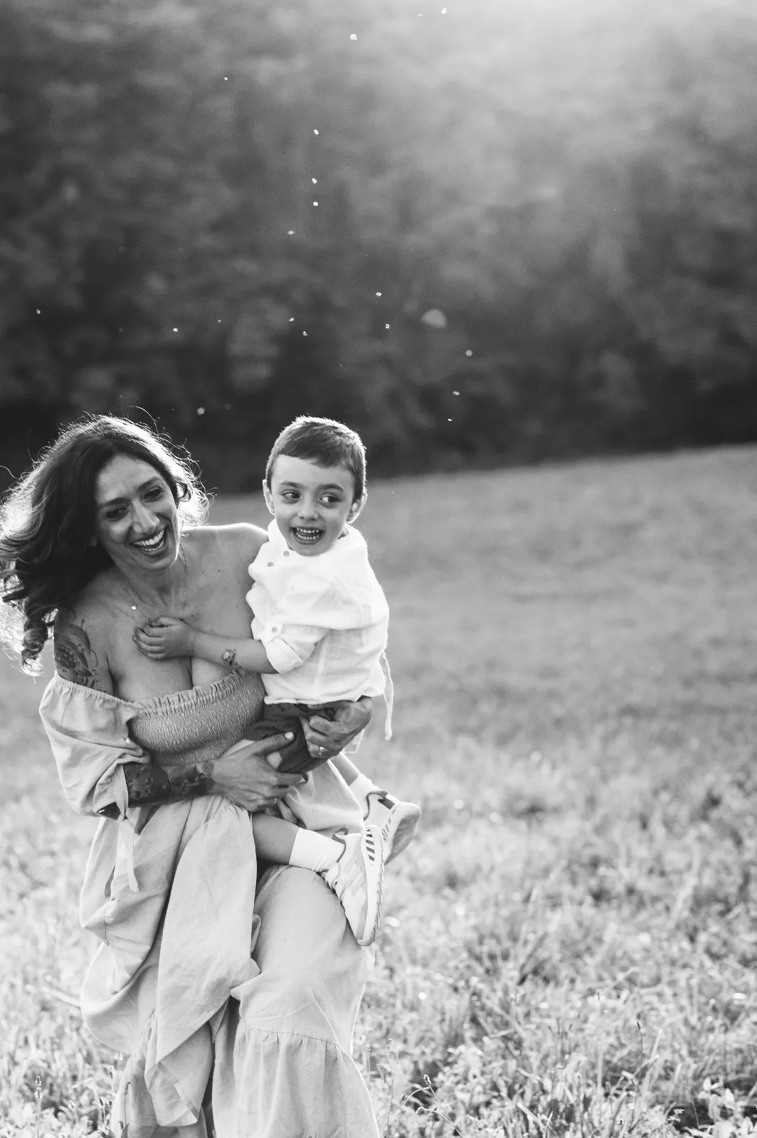 Servizio di famiglia in bianco e nero: mamma che tiene in braccio il figlio che ride tra le bolle di sapone