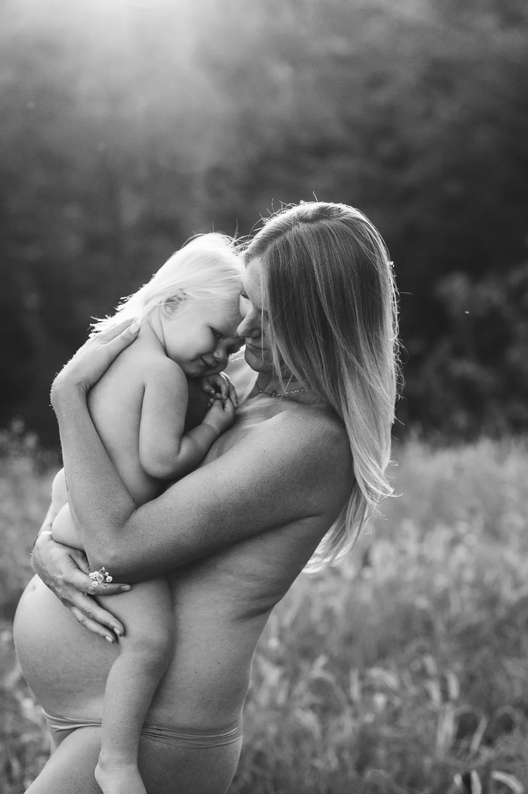 Servizio maternity in esterna in bianco e nero: mamma in attesa abbraccia il figlio piccolo, ritratto intimo