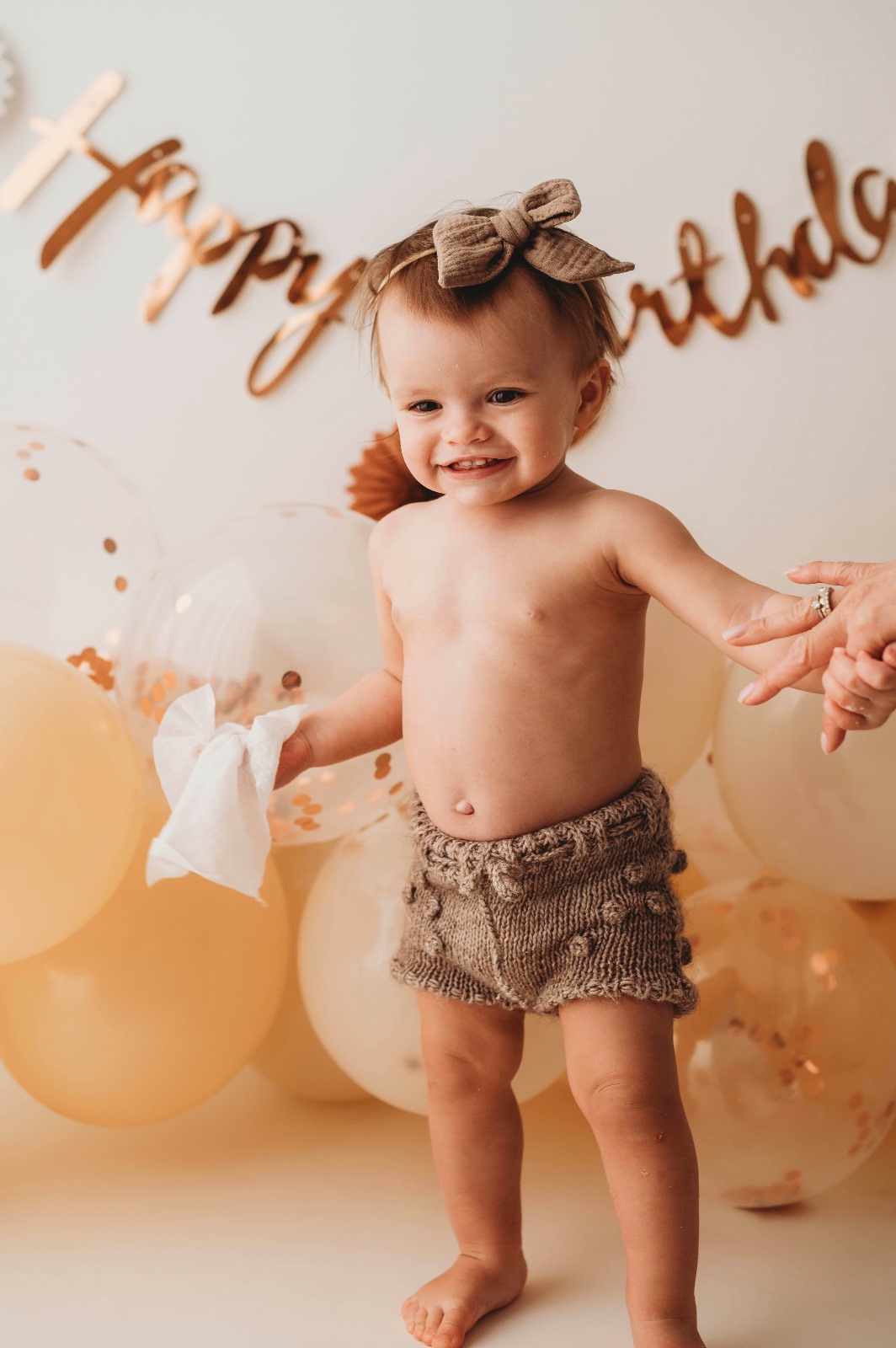 Servizio fotografico primo compleanno in studio: bimba in piedi davanti alla scritta Happy Birthday e ai palloncini