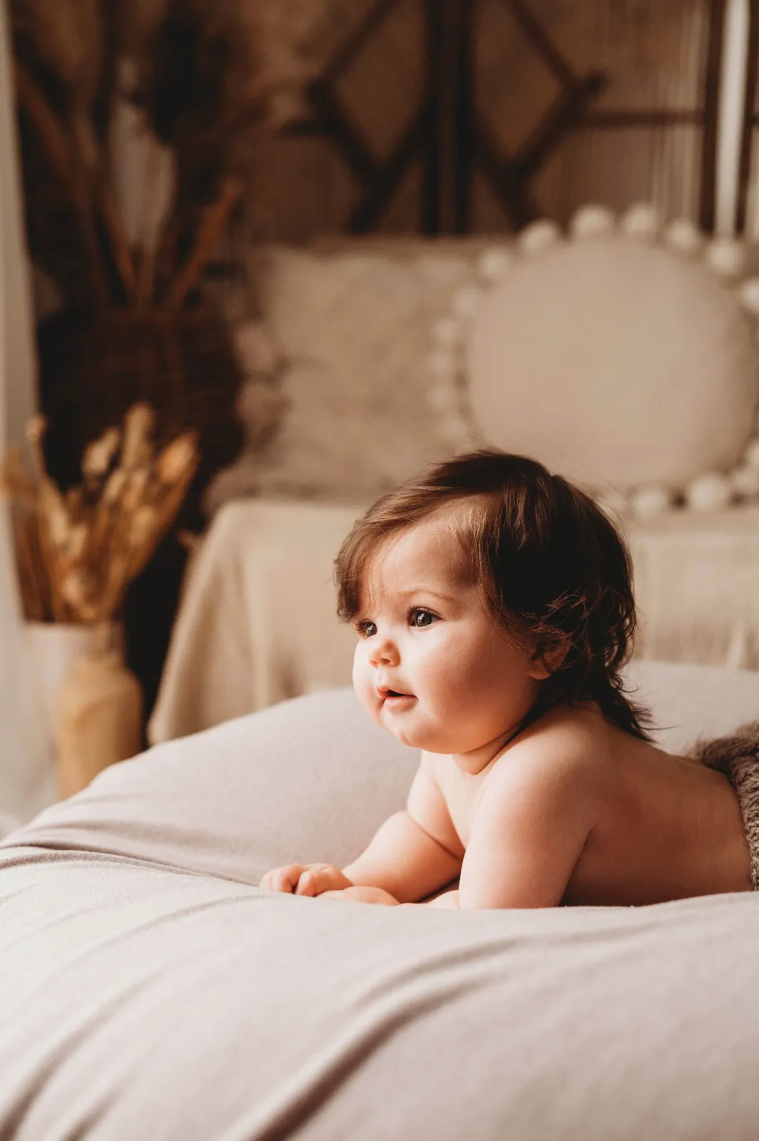 Mini sessione mom & me: il bebè a pancia in giù sul letto, in uno studio dai toni caldi