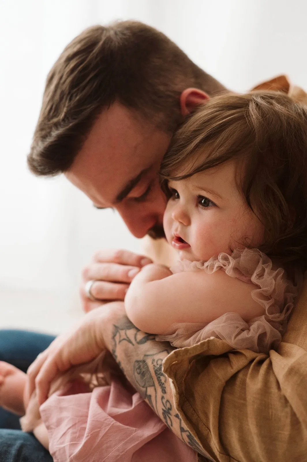 Servizio fotografico bebè in studio: papà abbraccia la bimba guancia a guancia