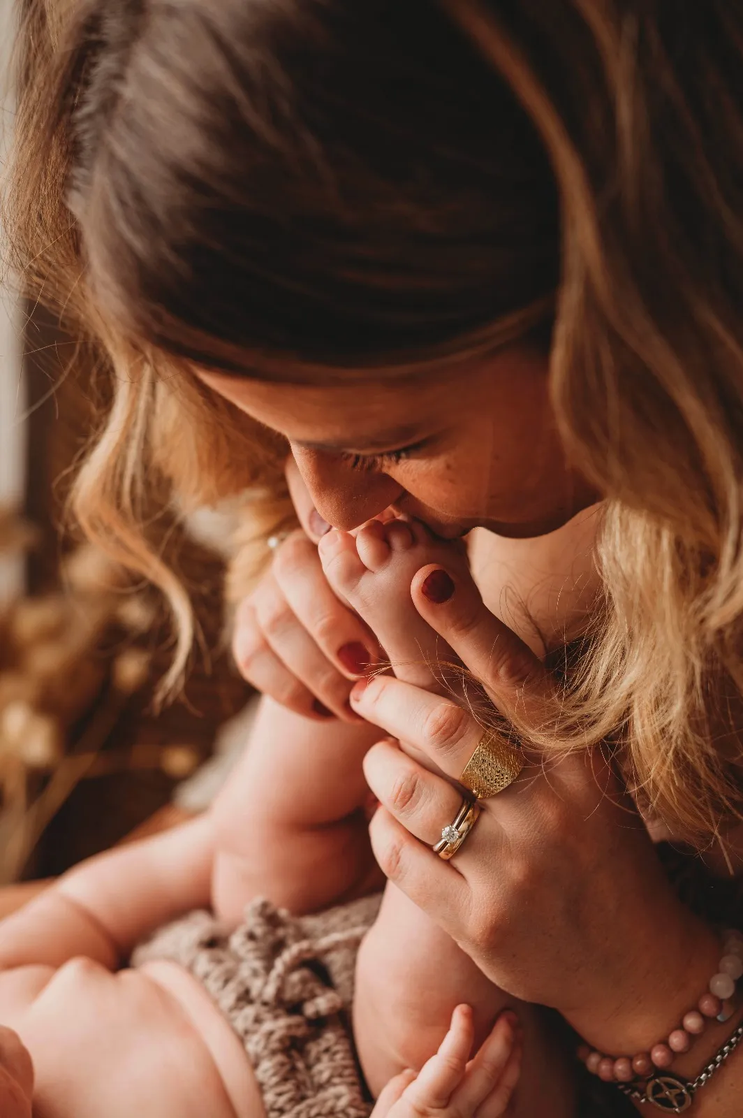 Servizio fotografico bebè: mamma che bacia i piedini del bimbo, luce calda