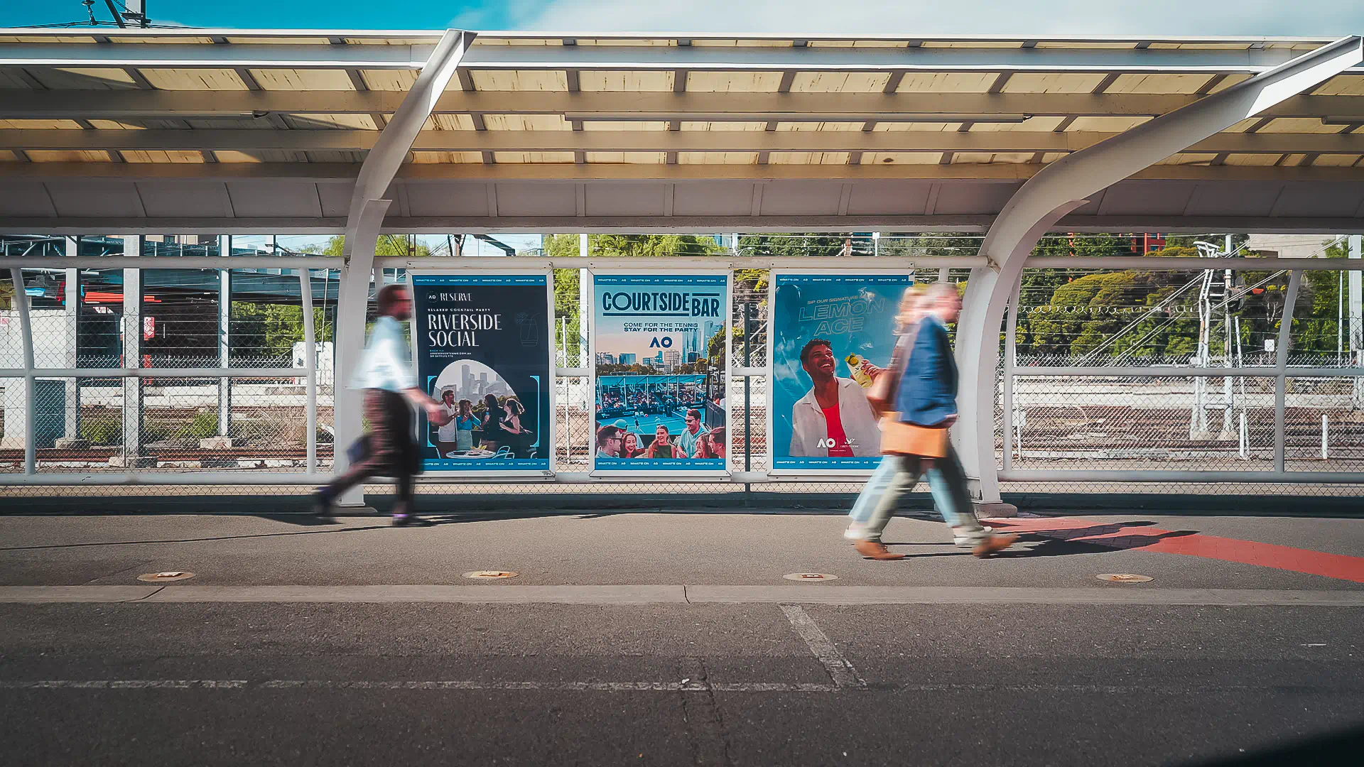people walking on a sidewalk with a covered walkway and posters