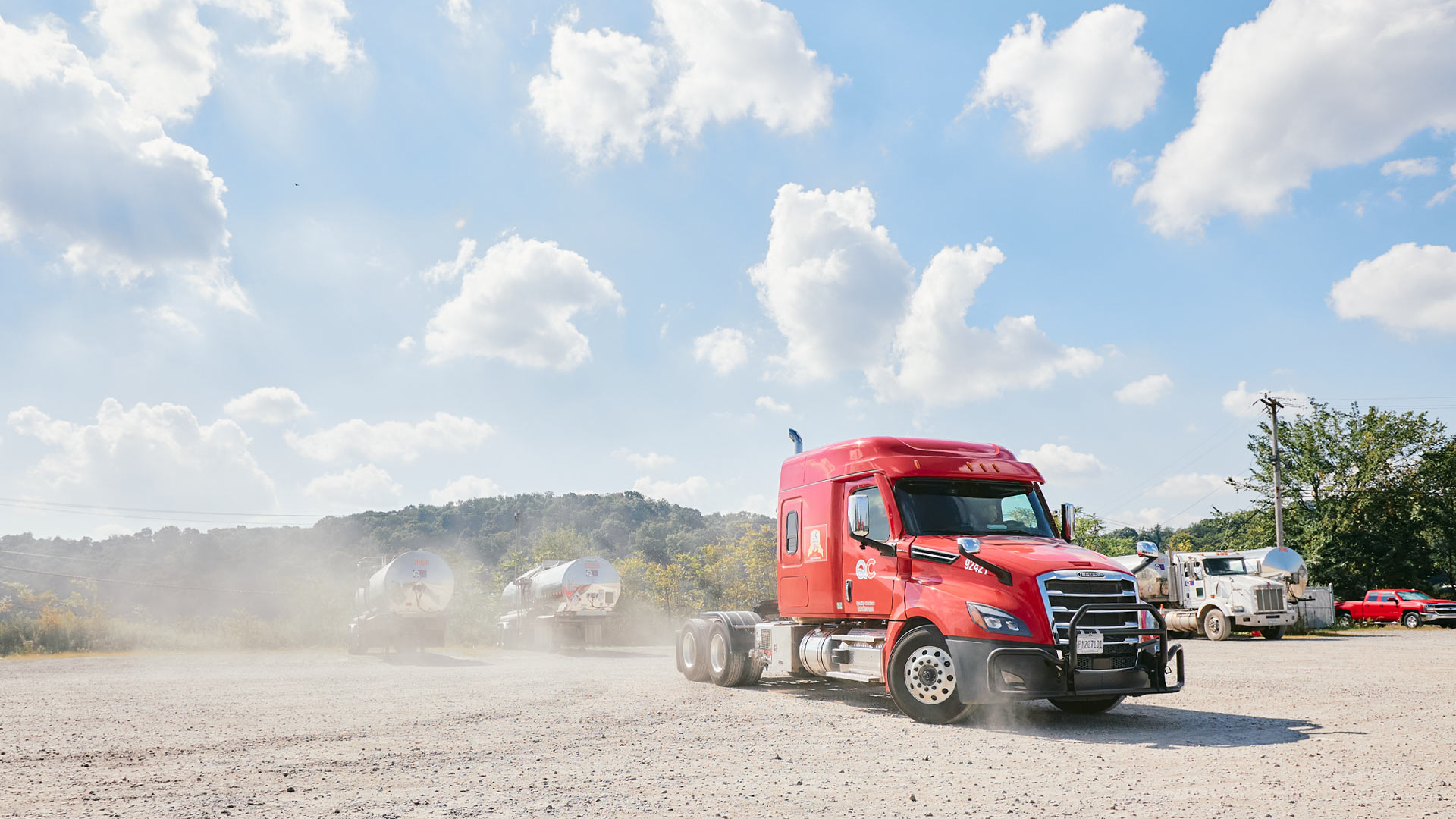 A red semi truck driving down a dirt road