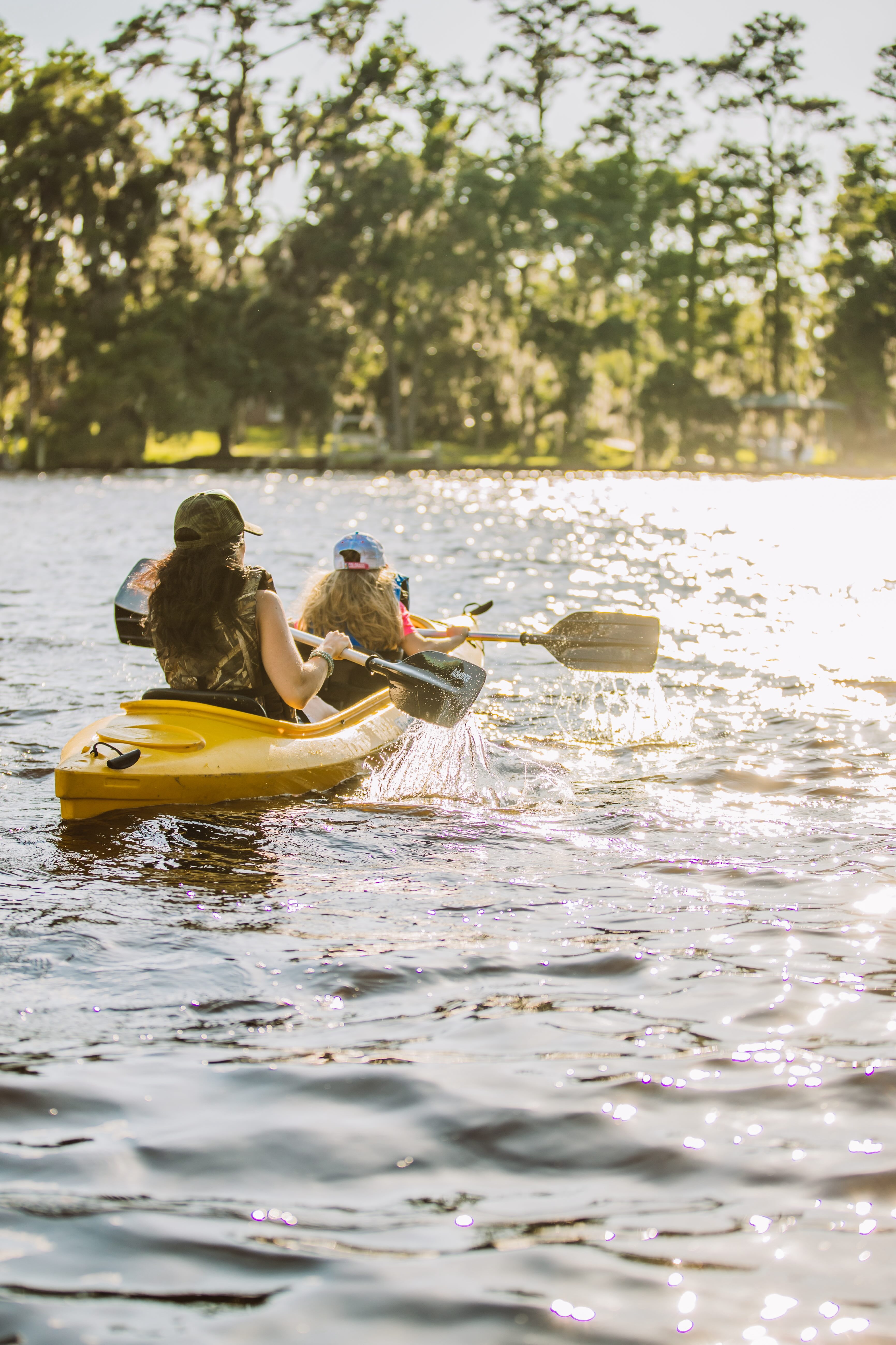 A couple of people riding on the back of a yellow kayak