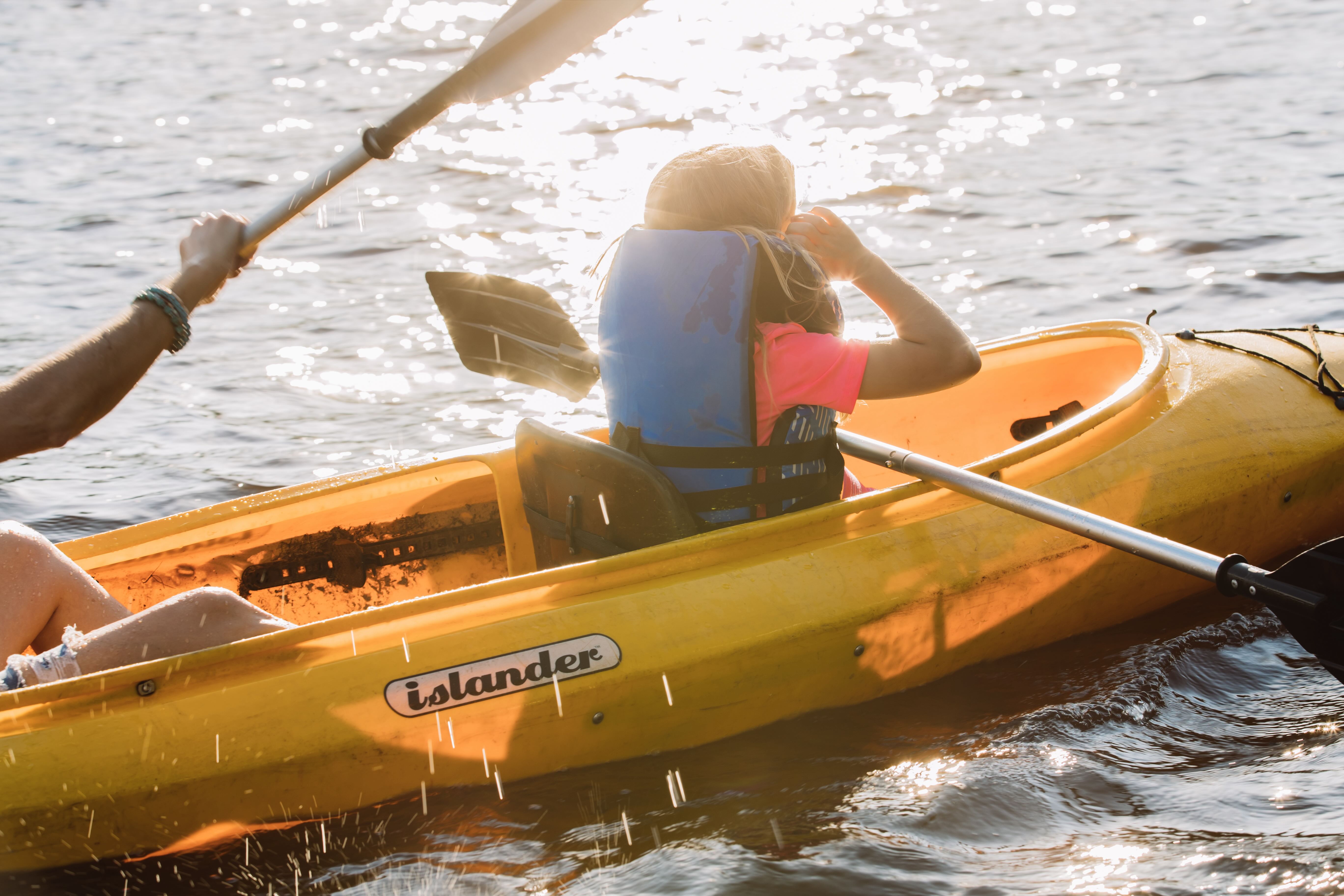 A man and a woman paddling a yellow kayak