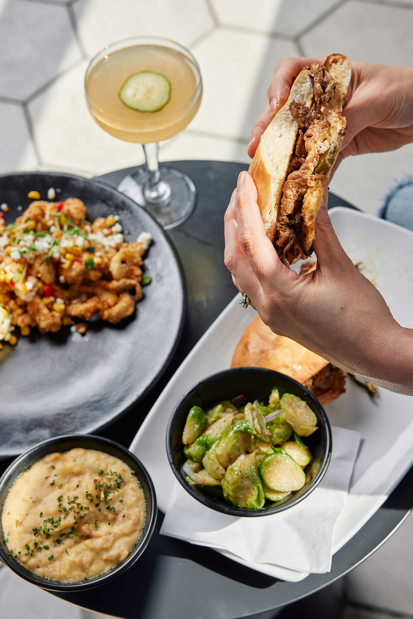 A person holding a sandwich over a plate of food