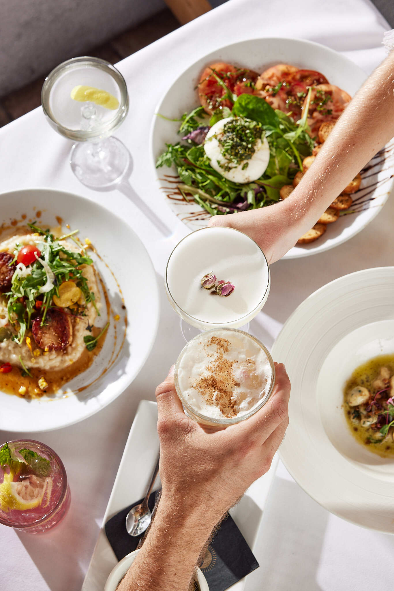 A person holding a wine glass over a plate of food