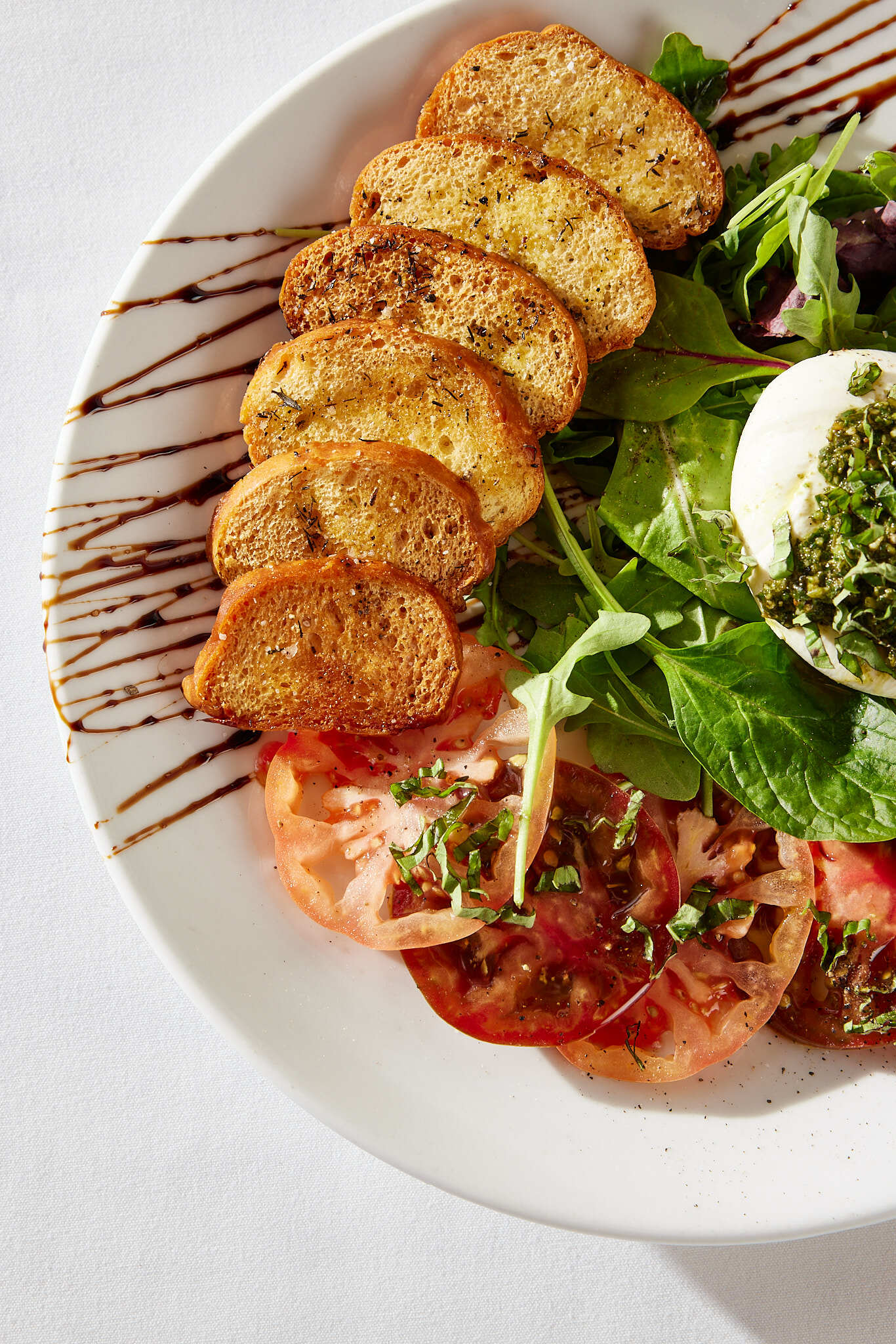 A white plate topped with a salad and slices of bread