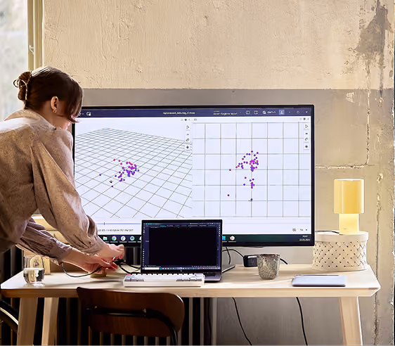 A woman at Sonair using a large monitor displaying scatter plots.