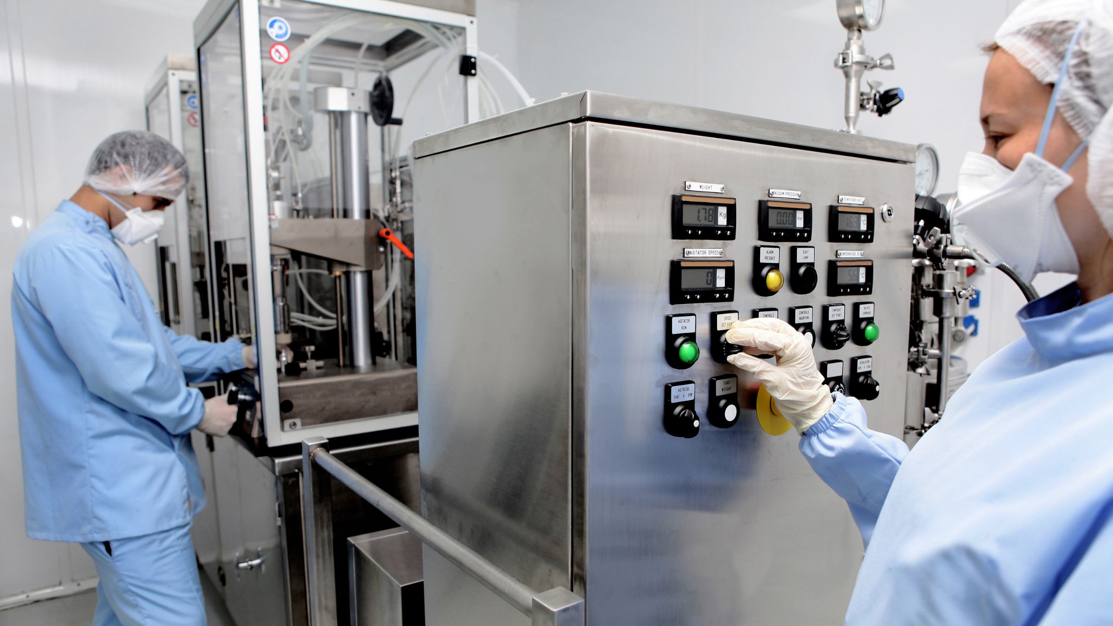 Two technicians working on a machine for pharmaceutical manufacturing 