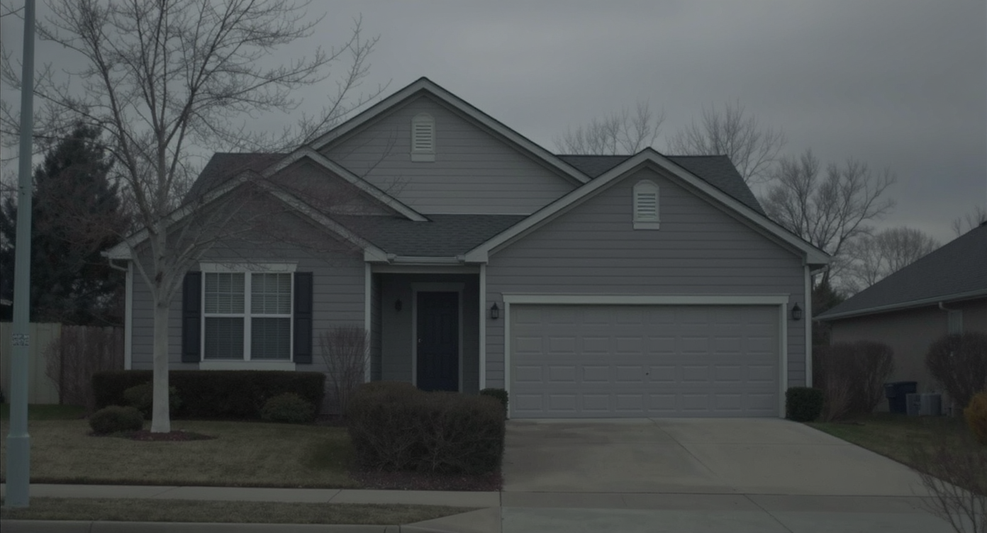 Two-story home photographed under dull, gray overcast sky, creating a muted, lifeless atmosphere.