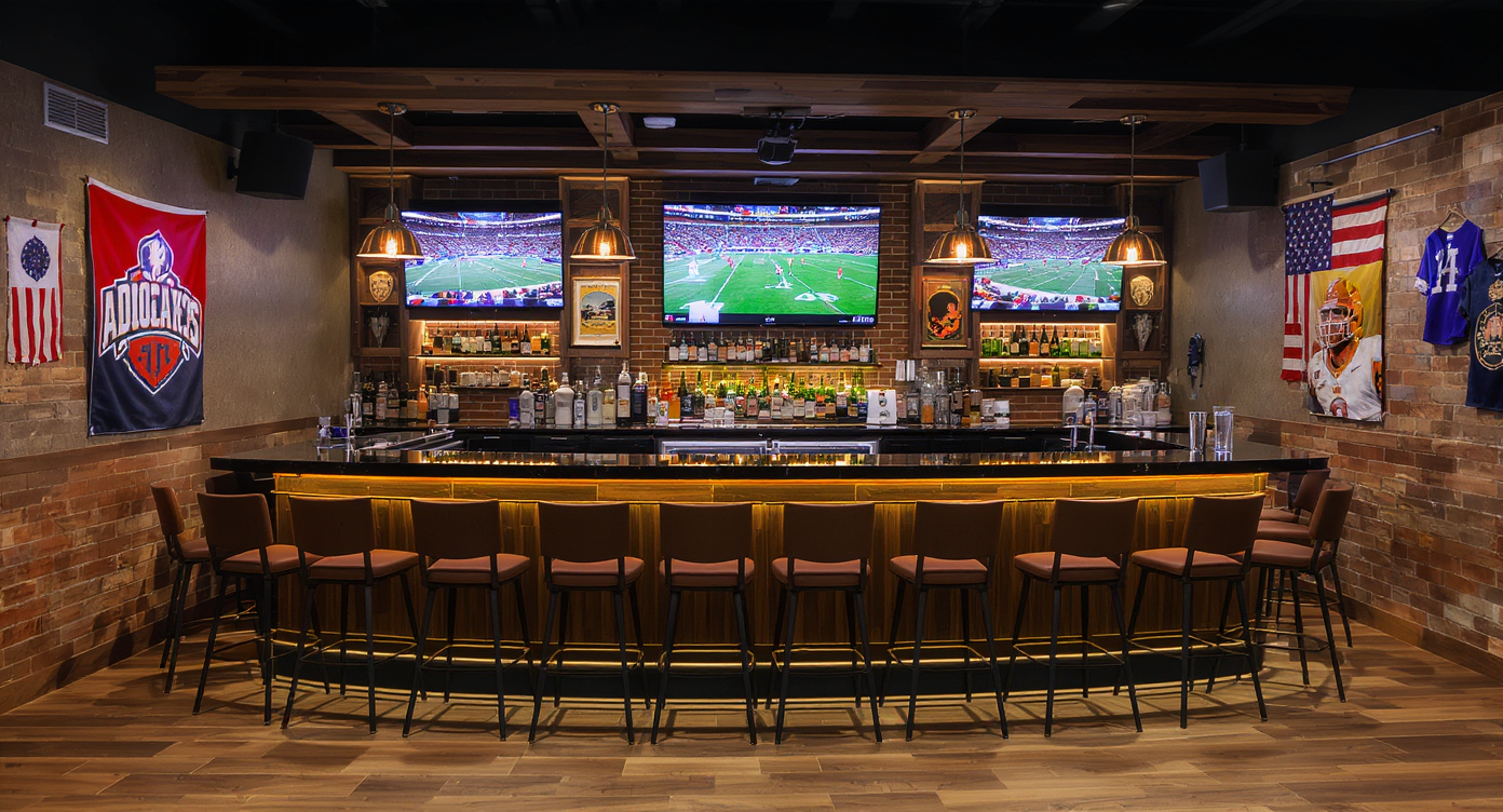 A sleek sports bar in a man cave equipped with a bar counter, stools, and several screens for sports viewing.
